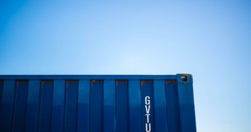 A blue shipping container against a blue sky. 