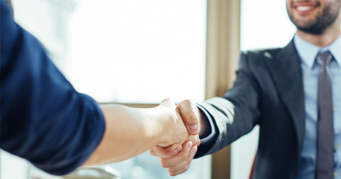 Two individuals are shaking hands inside an office.