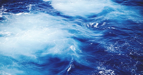 Aerial view of vibrant blue ocean waves with white foam.