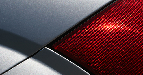 Close-up of a red car taillight against a sleek silver body.